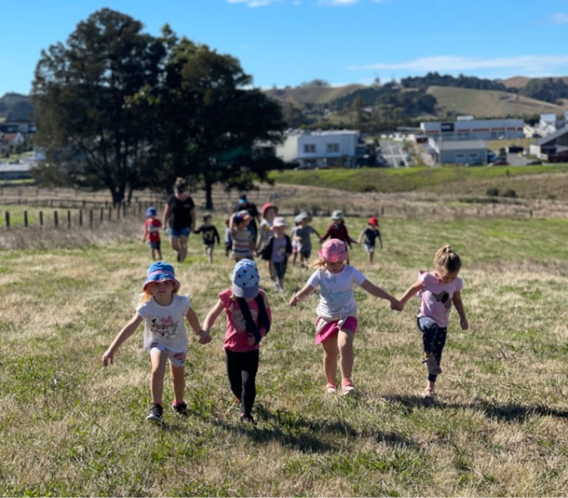 children holding hands running in a field